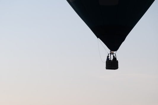un-grand-ballon-noir-volant-dans-un-ciel-bleu-KUly8cAvs9w