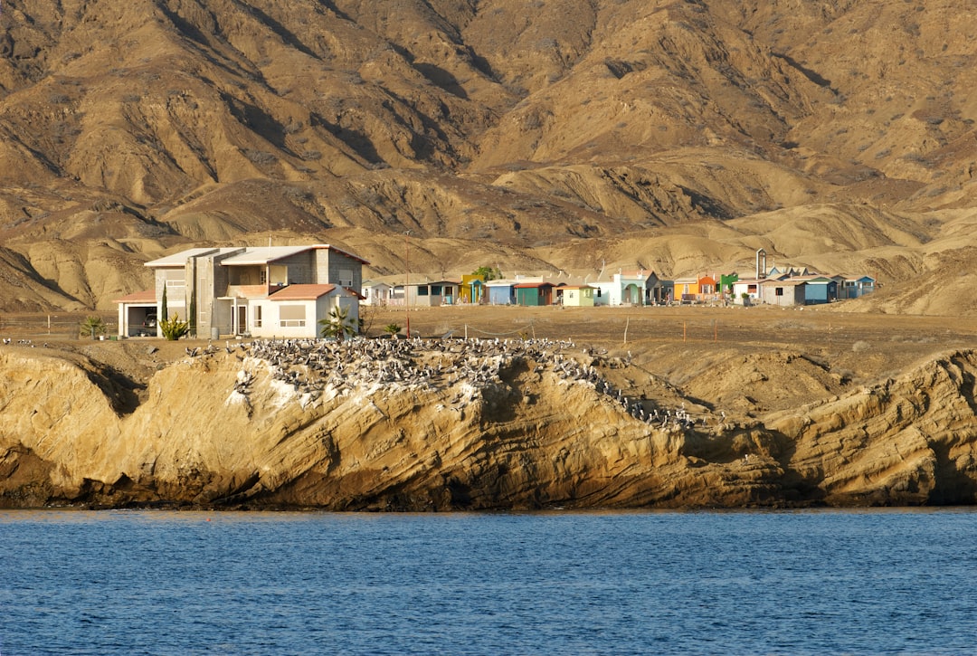 un-groupe-de-maisons-situees-au-sommet-dune-montagne-a-cote-dun-plan-deau-Kc84neVBgKg