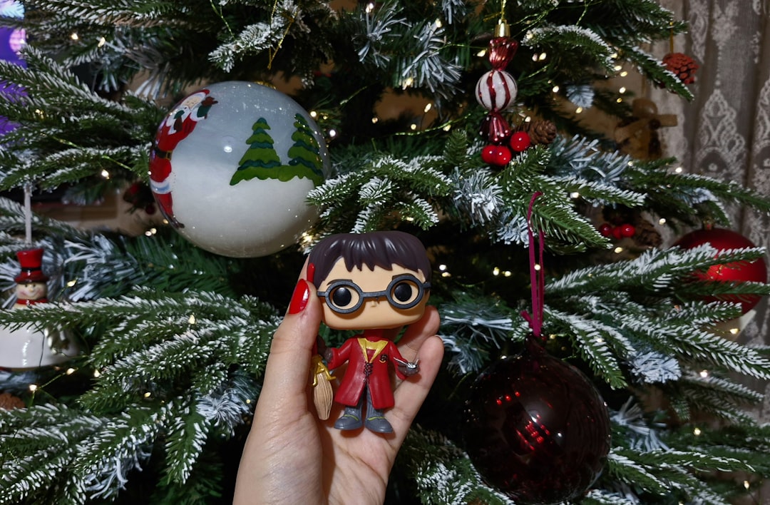 une-personne-tenant-une-petite-poupee-devant-un-arbre-de-noel-3WriVMe4A0U