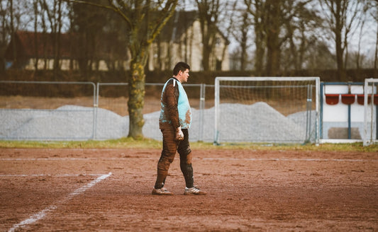 une-personne-debout-sur-un-terrain-de-terre-battue-avec-un-ballon-de-soccer-npBLKLjcKHM