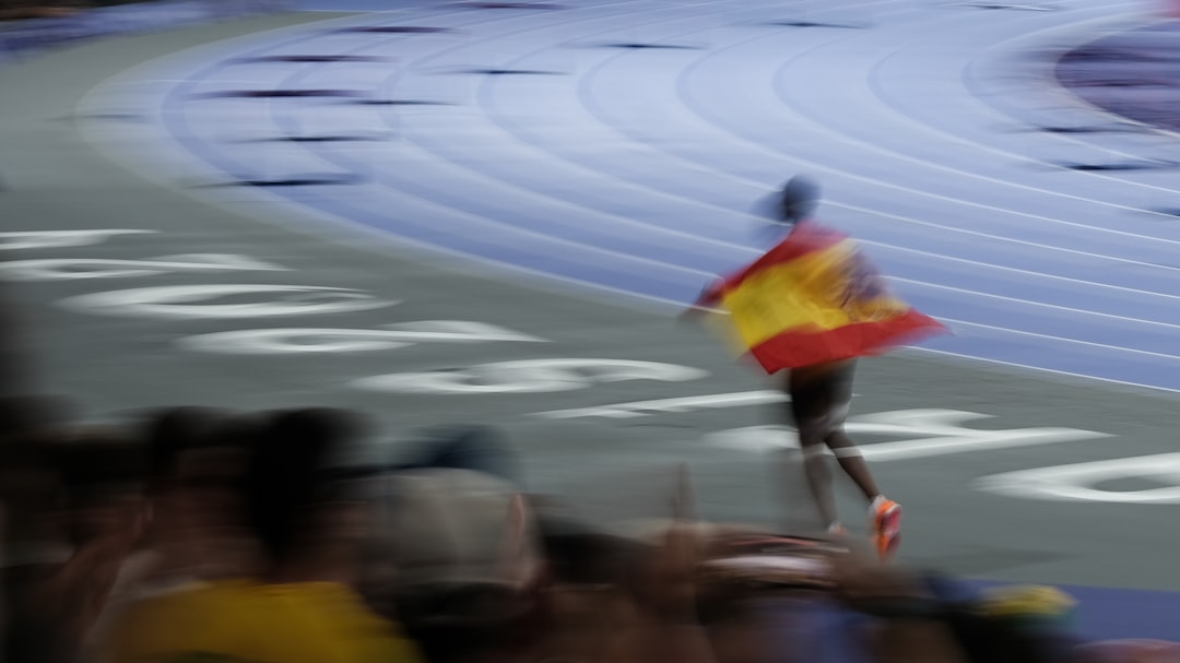 un-homme-tenant-un-drapeau-espagnol-au-sommet-dune-piste-de-course-3uuWDAzzdOE