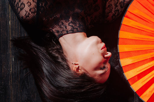une-femme-allongee-sur-le-sol-avec-un-eventail-orange-ay7Ip0gvOtE