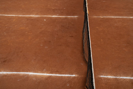 un-court-de-tennis-marron-avec-une-ligne-blanche-dessus-iWcprUMAi-U
