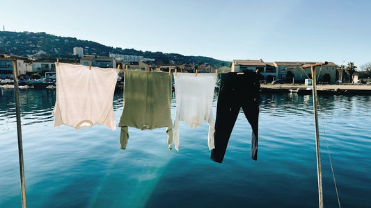 une-rangee-de-vetements-suspendus-a-une-corde-a-linge-au-dessus-dun-plan-deau-WaOj8hrH22g